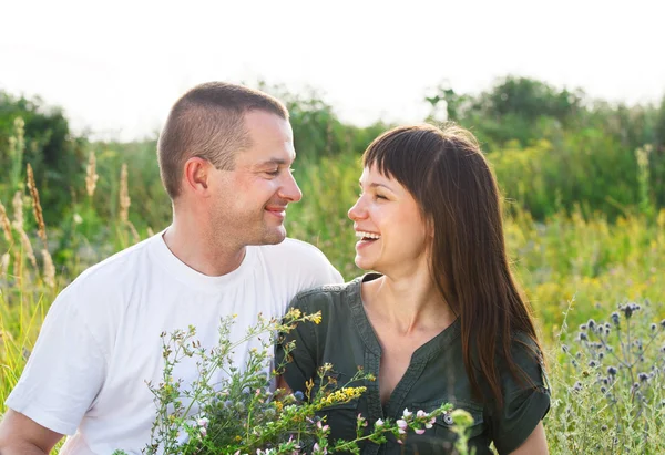 Happy young smiling couple with flowers — Stock Photo, Image