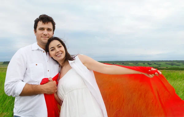 Young happy couple in love with red fabric in summer day — Stock Photo, Image