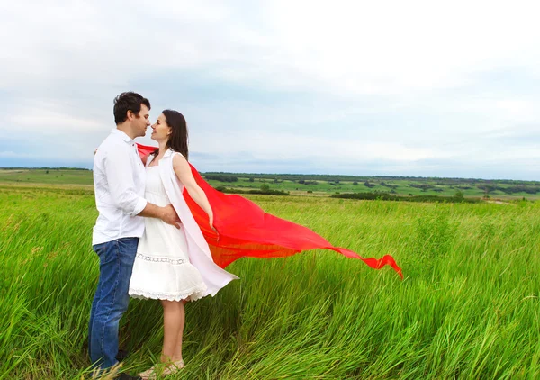 Jovem casal feliz apaixonado por tecido vermelho no dia de verão — Fotografia de Stock