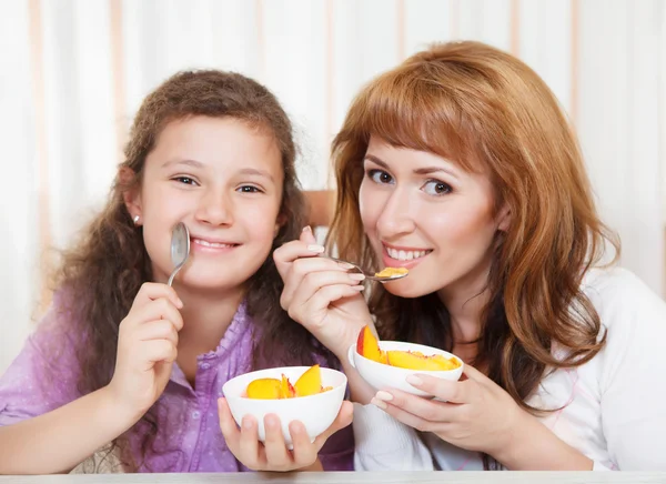 Matka a dcera jíst obiloviny a ovoce — Stock fotografie