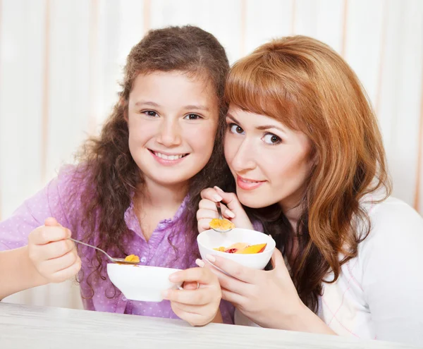 Madre e figlia mangiare cereali e frutta — Foto Stock