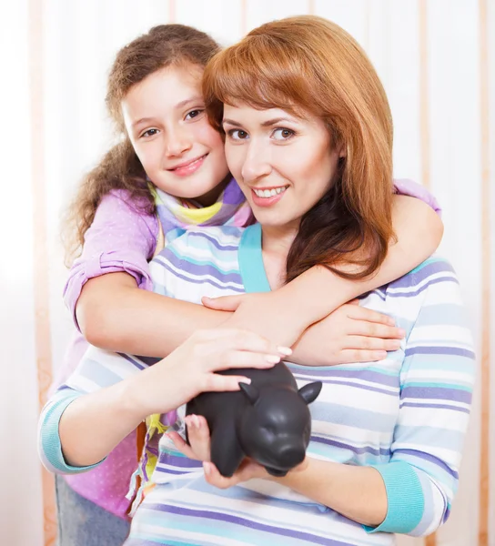 Klein meisje en moeder geld te besparen in een spaarpot — Stockfoto