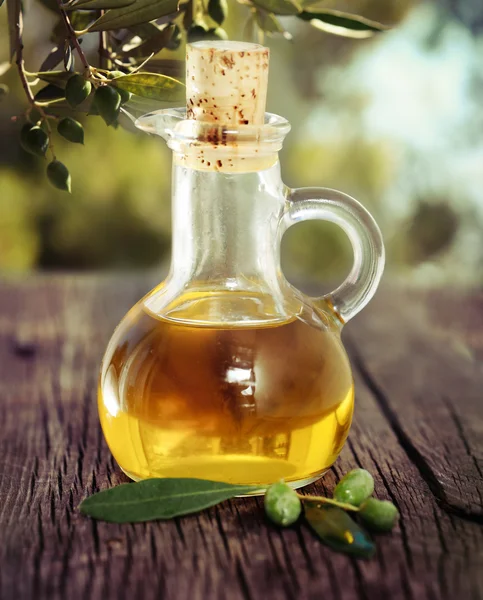 Aceite de oliva y rama de olivo sobre la mesa de madera —  Fotos de Stock