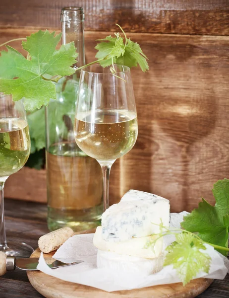 Glasses of white wine, bottle and cheese — Stock Photo, Image