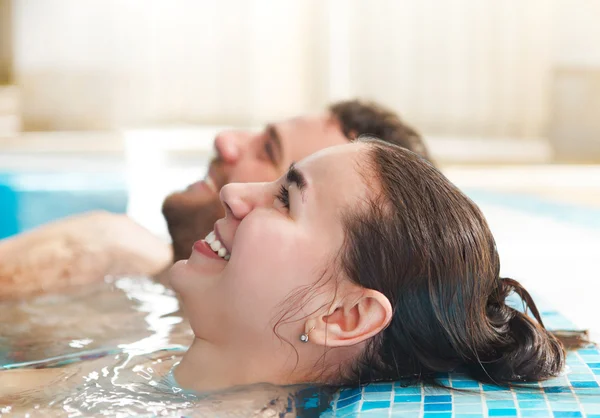 Casal jovem relaxante na água em um resort de spa — Fotografia de Stock