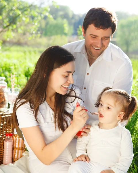 Feliz familia joven con la niña en un picnic — Foto de Stock