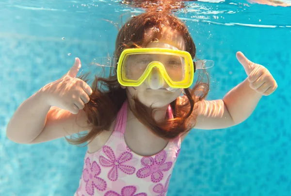 Das kleine Mädchen schwimmt unter Wasser und lächelt — Stockfoto