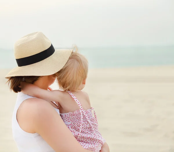 Portret van moeder houden haar baai meisje op strand — Stockfoto