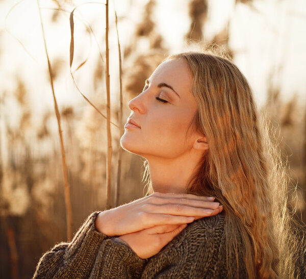 Портрет улыбающейся блондинки, отдыхающей на открытом воздухе осенью
