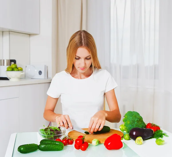 Ung kvinna skära grönsaker — Stockfoto