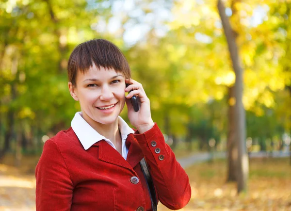 Fiatal szép, mosolygós nő mobiltelefonon beszél — Stock Fotó