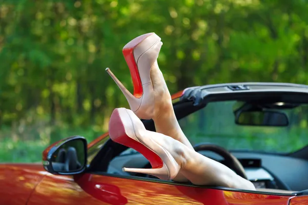Woman legs in high heels out the windows in car — Stock Photo, Image