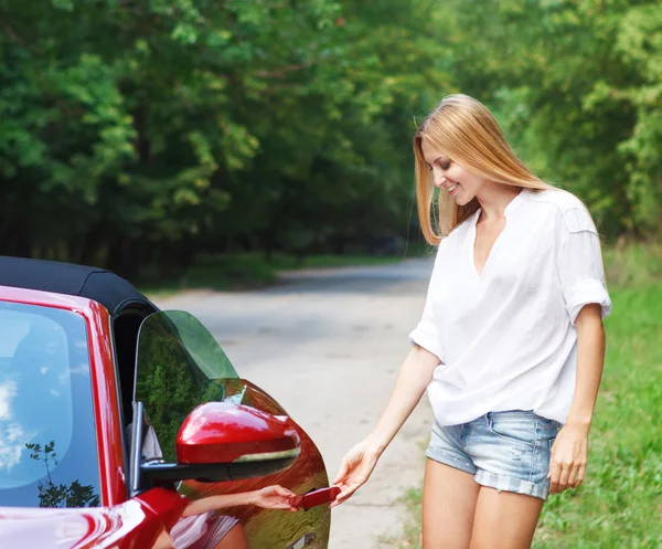 Young woman opening a sports car — Stock Photo, Image
