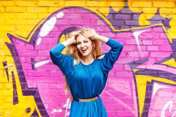 Young attractive blond girl near the wall with graffiti — Stock Photo, Image