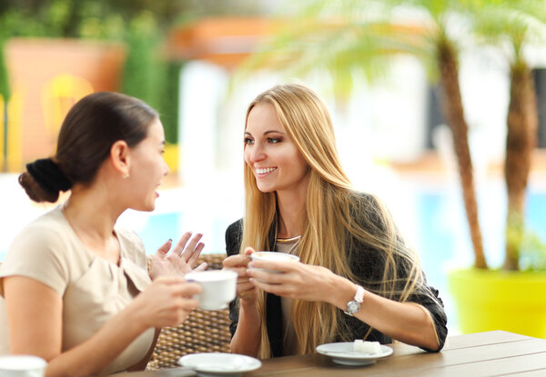 Young women drinking coffee in a cafe outdoors