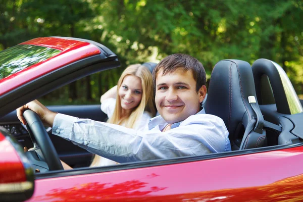 Couple in red cabriolet in a sunny day — Stock Photo, Image