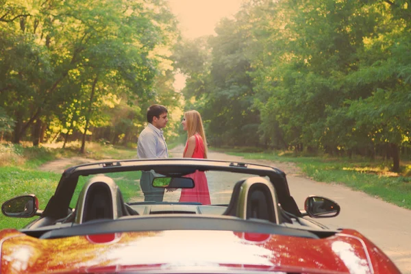 Jeune couple heureux debout près de voiture rouge — Photo