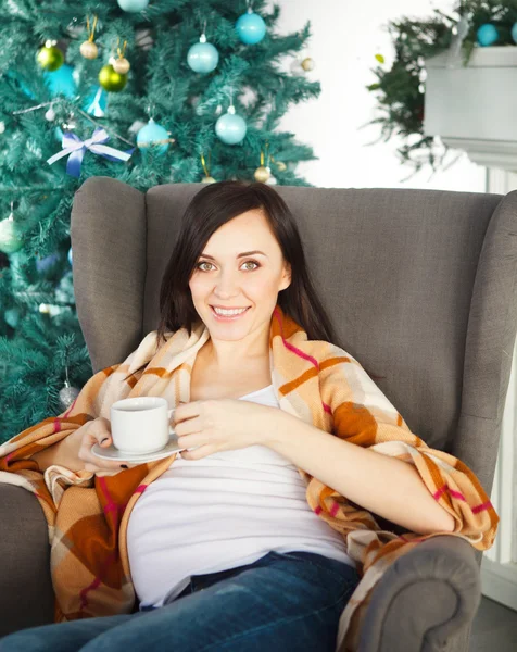 Glückliche junge schwangere Frau sitzt im Sessel — Stockfoto