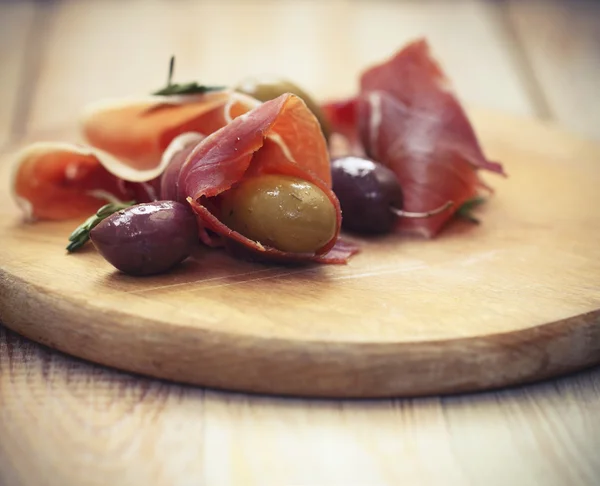 Prosciutto with olives and rosemary — Stock Photo, Image