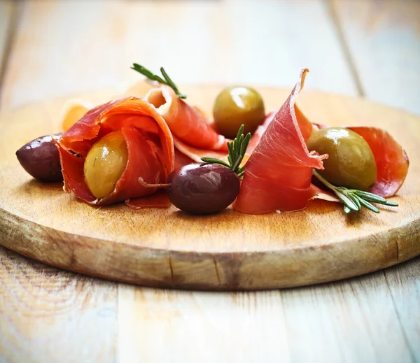 Prosciutto with olives and rosemary — Stock Photo, Image