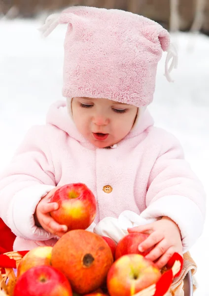 Счастливый улыбающийся ребенок с яблоком в зимний день — стоковое фото