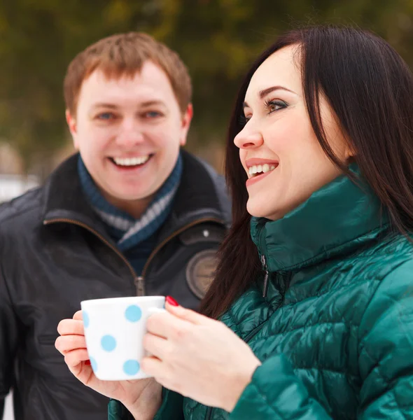 Casal feliz se divertindo no parque de inverno bebendo chá quente — Fotografia de Stock