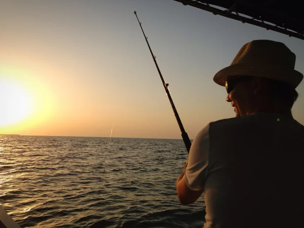 Uomo di pesca in barca al tramonto — Foto Stock