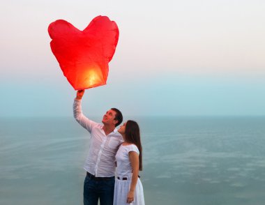 jong koppel start een rode chinese hemel lantaarn in de schemering