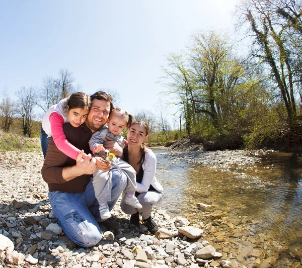 Feliz familia joven con dos hijas pequeñas cerca de la montaña r —  Fotos de Stock