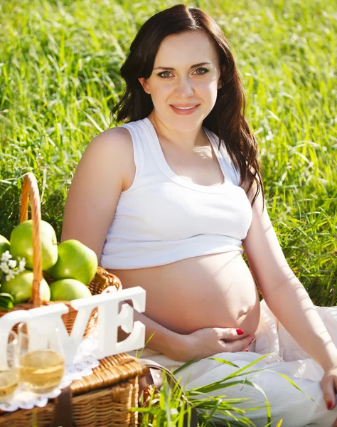 Krásná těhotná žena v bílém v parku na jaře — Stock fotografie