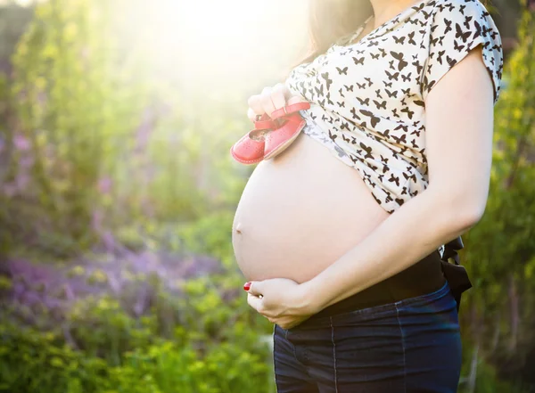 Zamknij się nie do poznania w ciąży kobiety z dziecka małe buty — Zdjęcie stockowe