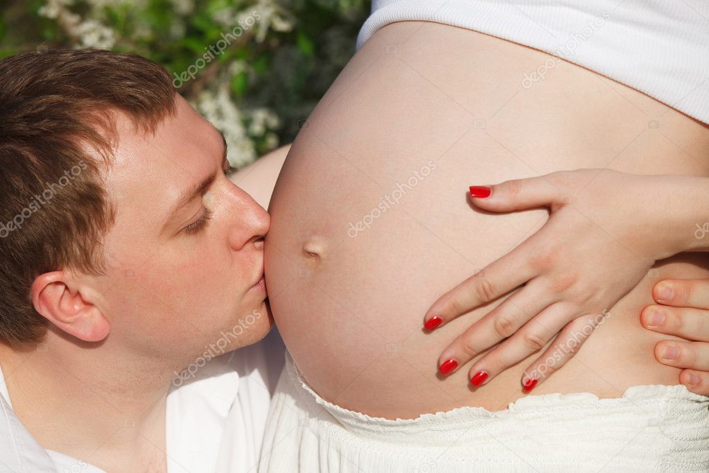 Young happy pregnant couple in the flowering spring park