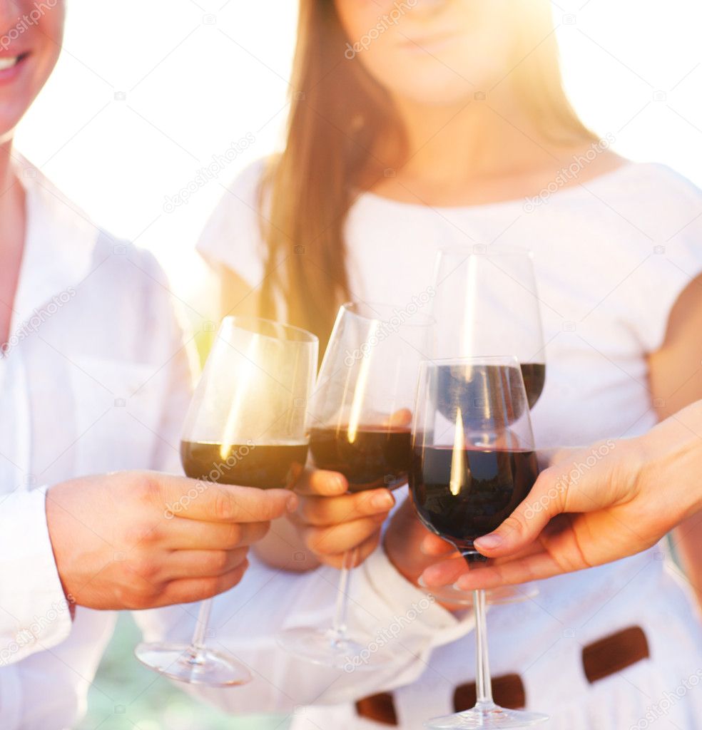 People holding glasses of red wine making a toast