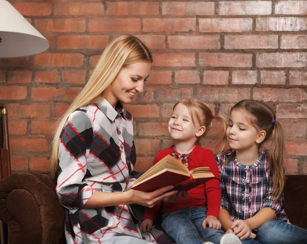 Mãe feliz e suas filhas dentro de casa. Fundo de tijolo — Fotografia de Stock