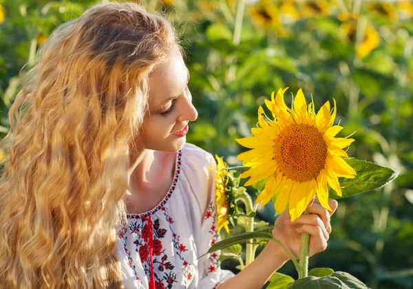 Gelukkig jonge vrouw met lange haren in de zonnebloem veld — Stockfoto