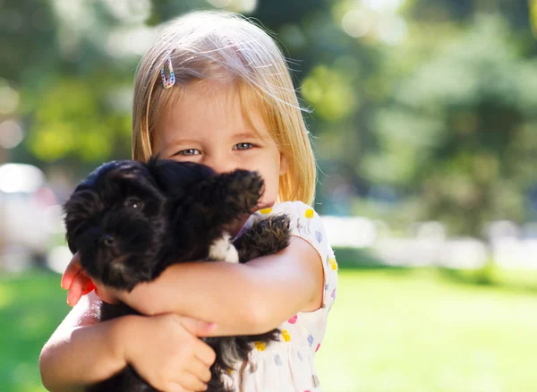 Schattige kleine meisje knuffelen hond puppy — Stockfoto