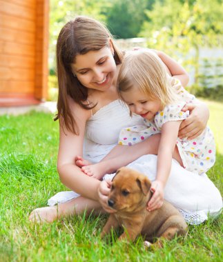 Cute little girl and her mother hugging dog puppies clipart