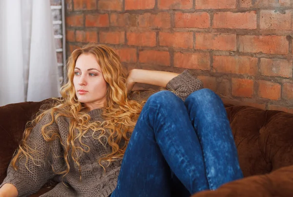 Счастливая молодая красивая женщина, отдыхающая на диване дома — стоковое фото