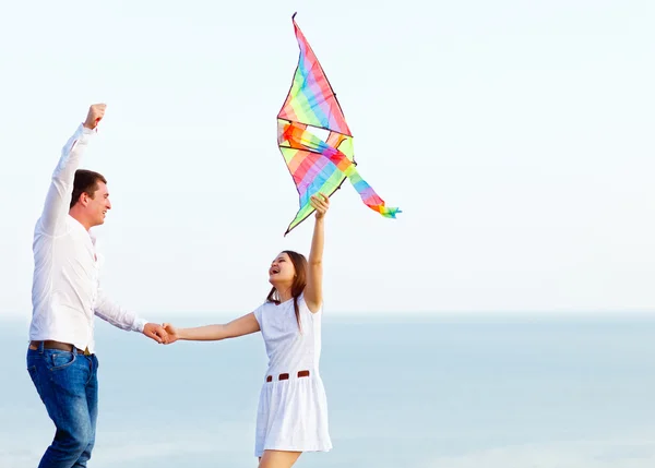 Happy couple in love with flying a kite on the beach — Stock Photo, Image