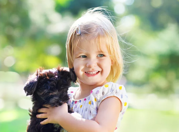 Cute little girl hugging dog puppy outdoors — Stock Photo, Image