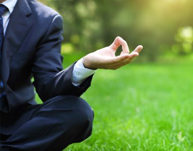 iş adamı rahat lotus pozisyonunda bir parkta 