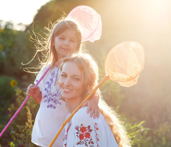 Mère joyeuse et sa fille jouant dans un champ avec un insecte — Photo