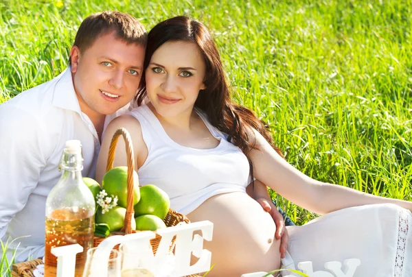 Young happy pregnant couple in the flowering spring park — Stock Photo, Image