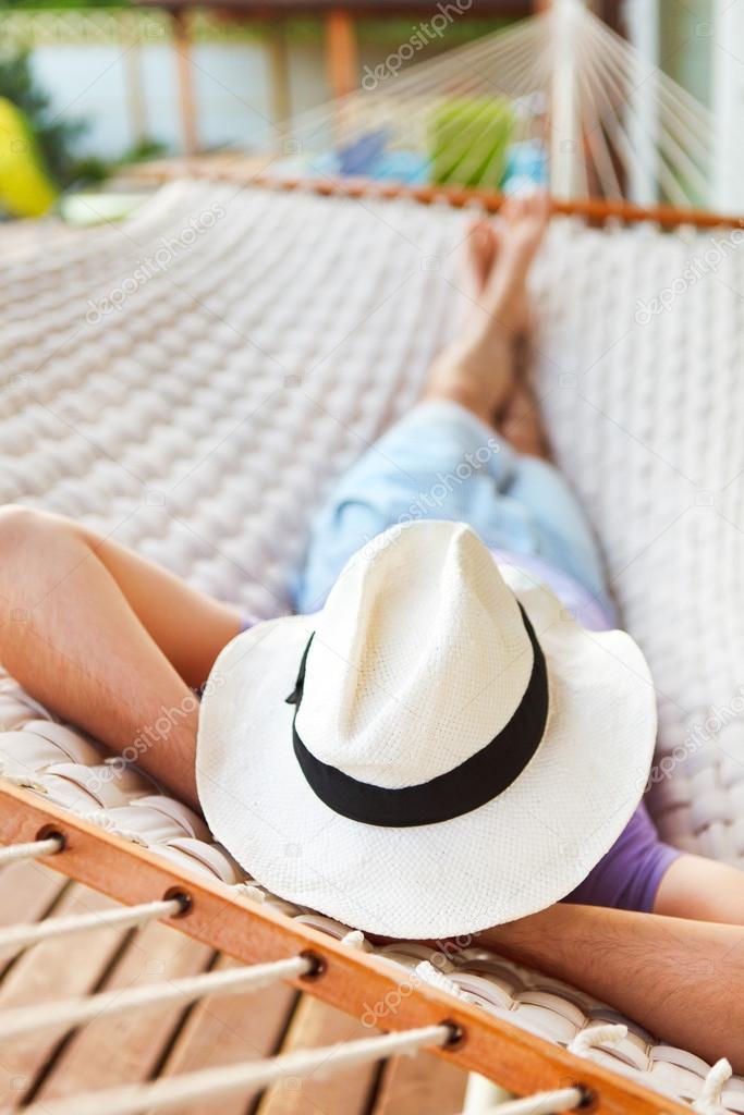 Man in hat in a hammock on a summer day