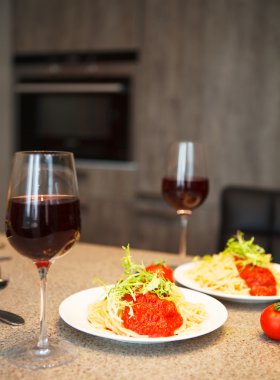 Spaghetti with tomato sauce and red wine in a kitchen clipart