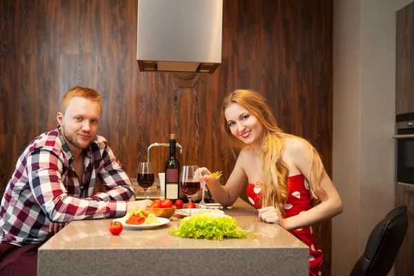 Happy couple in a kitchen eating pasta in a kitchen — Stock Photo, Image