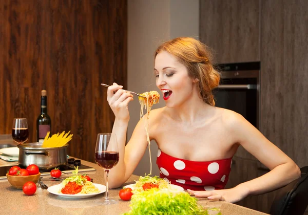 Sexy joven rubia comiendo espaguetis en la cocina — Foto de Stock