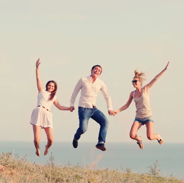 Happy vrienden springen op het strand — Stockfoto