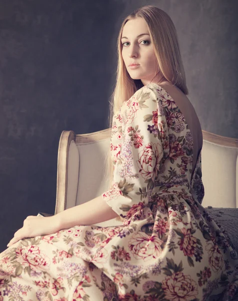 Beautiful blond girl in long dress in living room — Stock Photo, Image