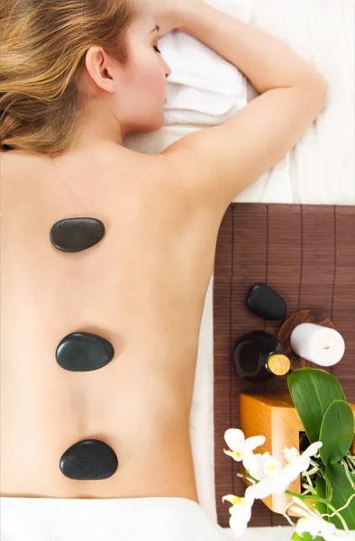 Mujer joven recibiendo masaje de piedra caliente en el salón de spa —  Fotos de Stock